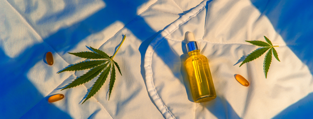 Cannabis leaves and bottle of cannabis on bed sheet